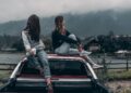 two women sitting on vehicle roofs