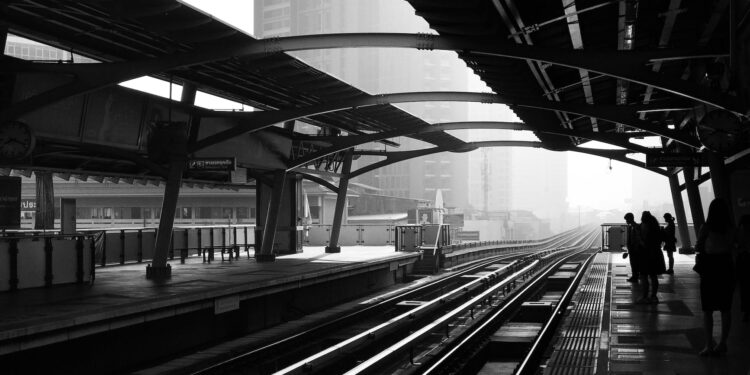 silhouettes of anonymous people standing on railway platform
