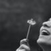 smiling woman holding dandelion flower