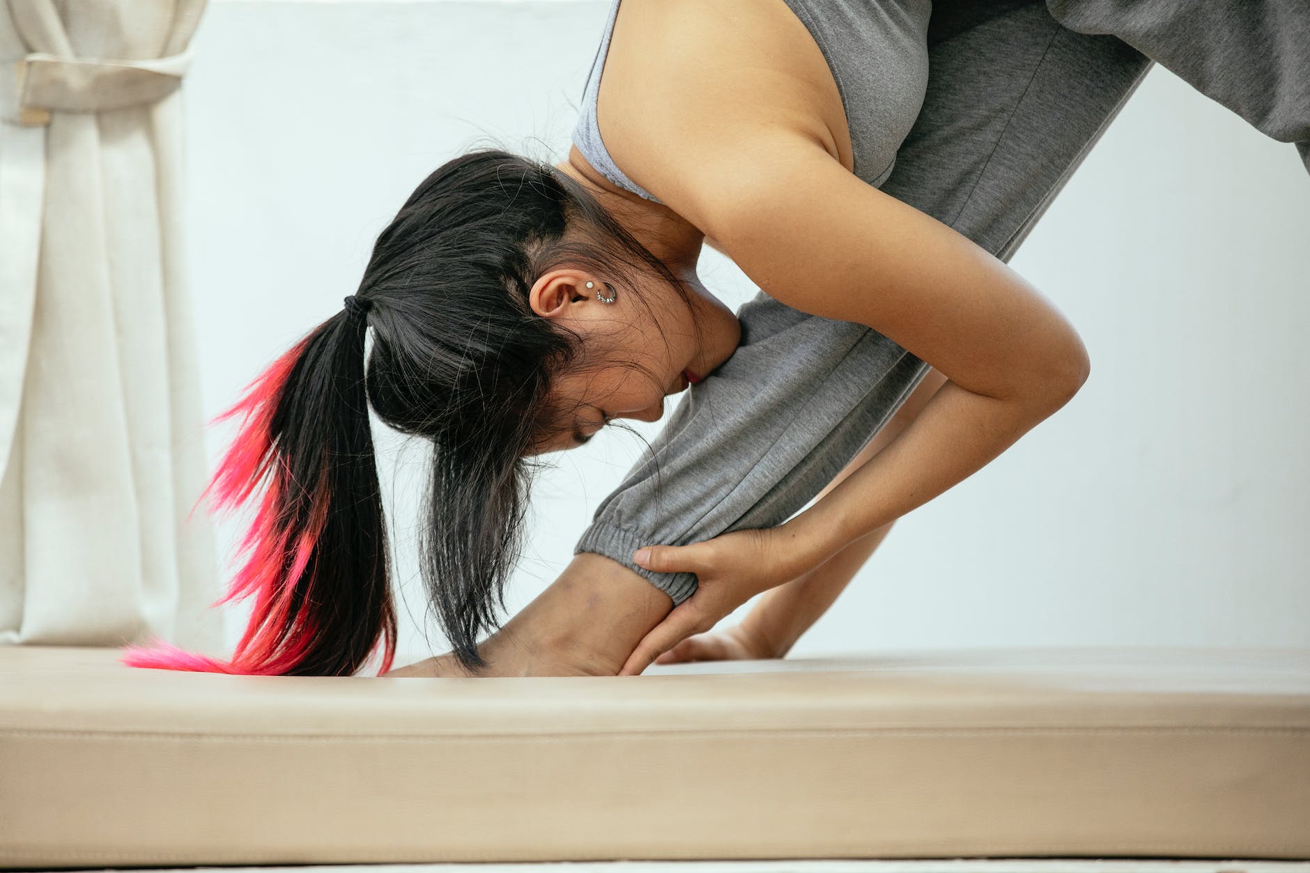 calm ethnic woman doing yoga in pyramid pose