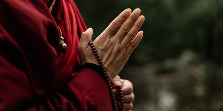 hands holding a brown prayer beads
