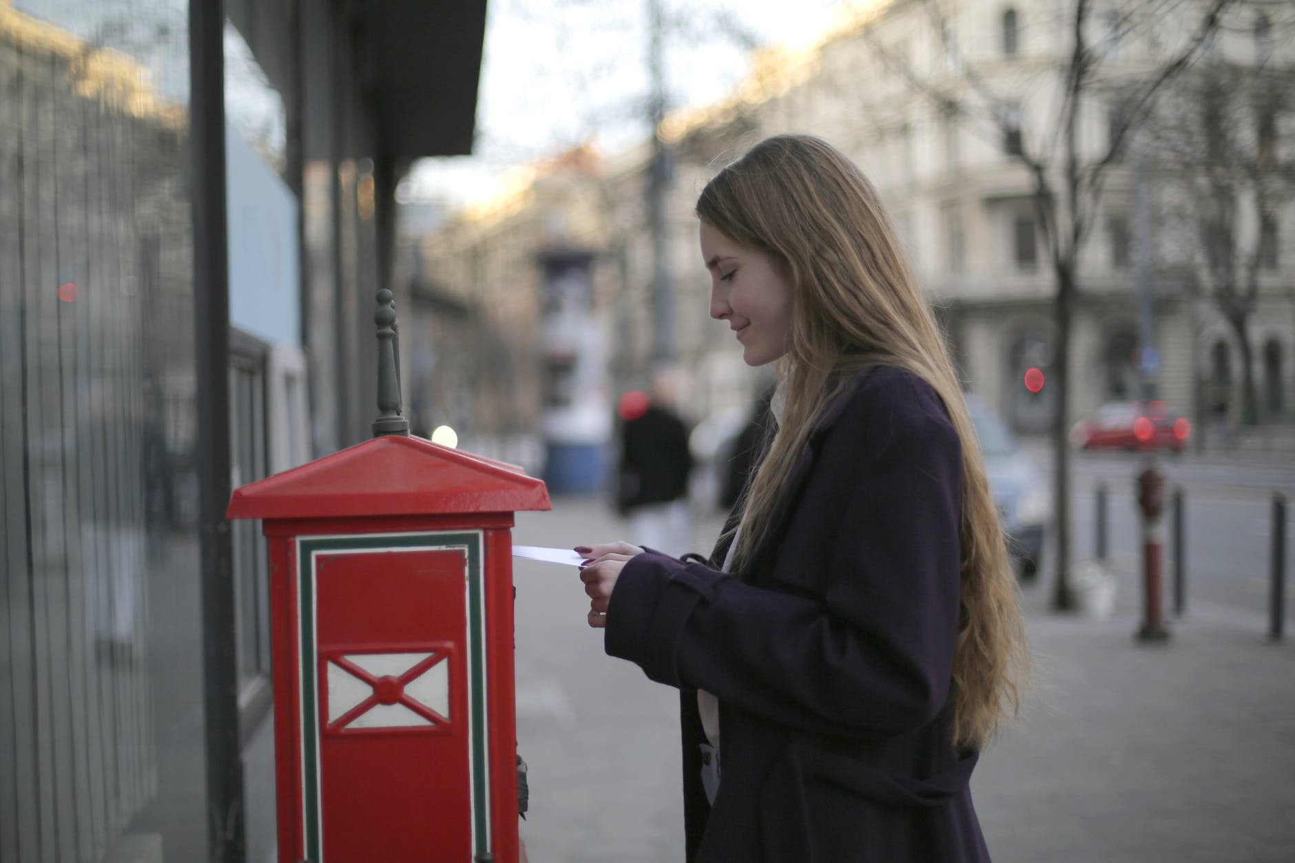 woman in black coat standing beside red telephone post office box | Guest posting sites, ideas and strategies